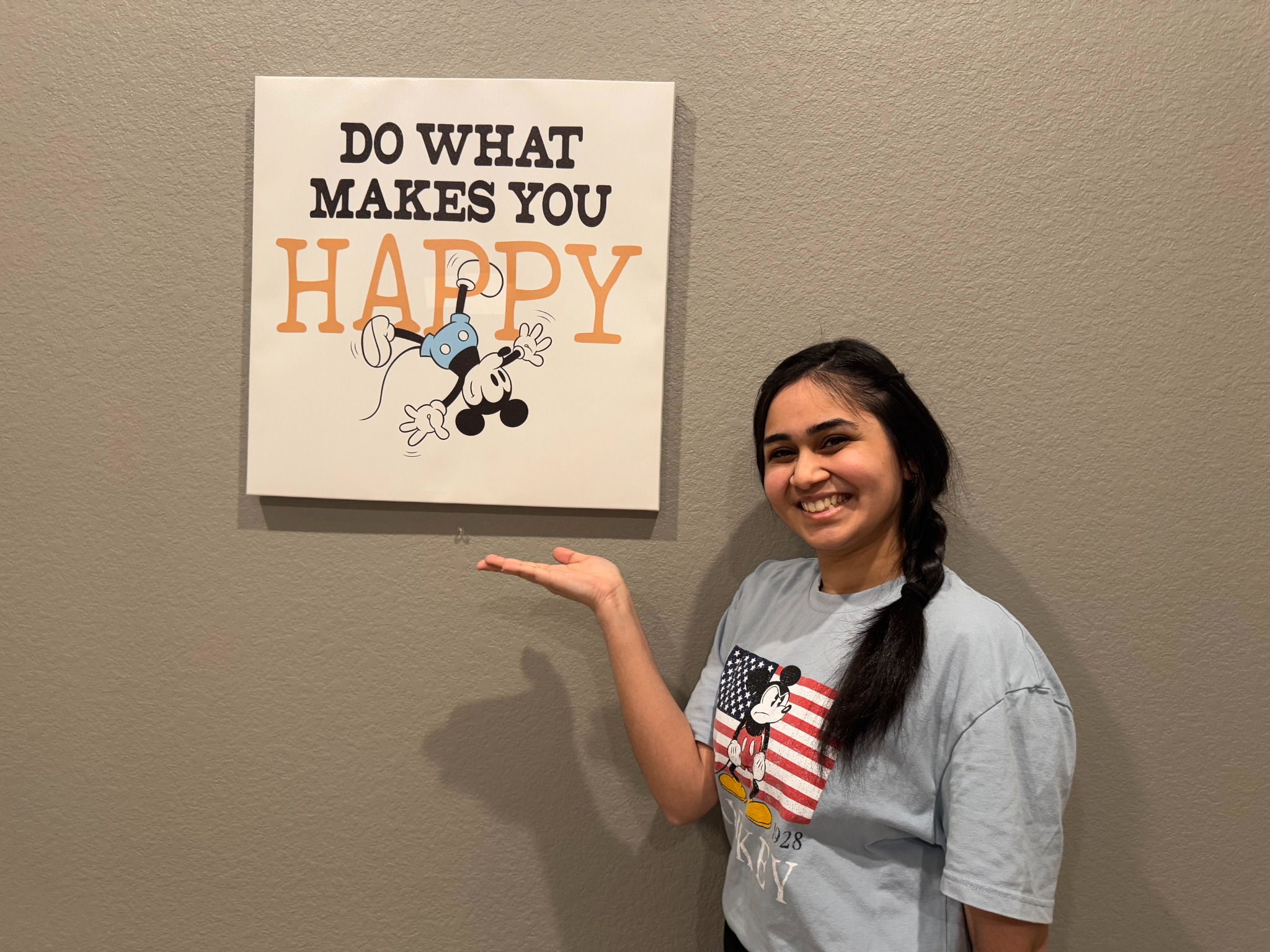 Isha smiling beside a do what makes you happy sign